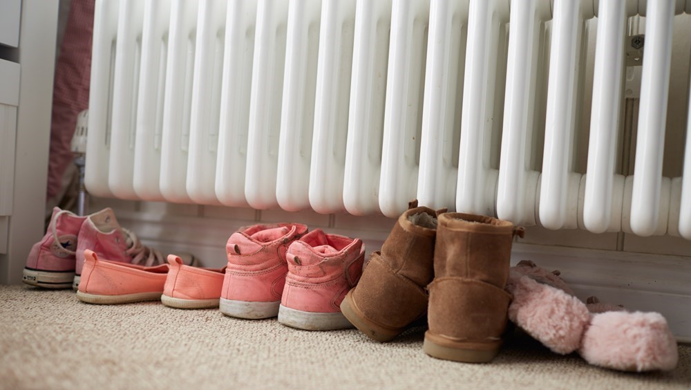 Børnesko står ved siden af hinanden under radiator