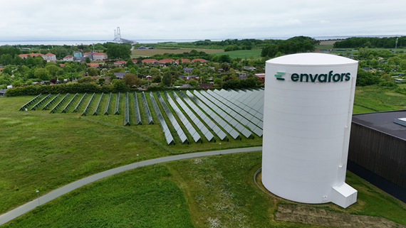 Dronebillede af Halsskov Varmeværk med en solcellemark og Storebæltsbroen i baggrunden